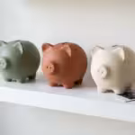 A person smiling at a laptop in a bright home office, representing financial relief and success.
