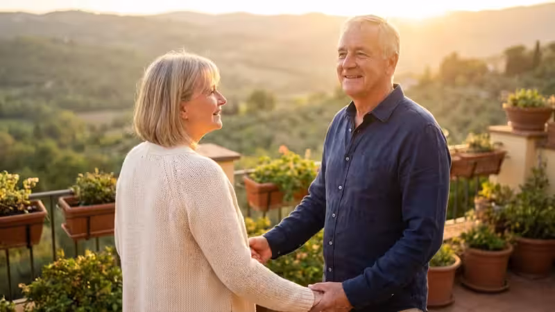 A mature couple looking at a scenic horizon from a balcony during golden hour.