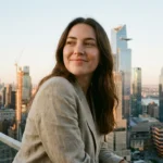A woman sitting at a bright, organized desk looking at a laptop with a sense of relief.