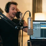 A woman recording voiceover in a sunlit, professional home studio.